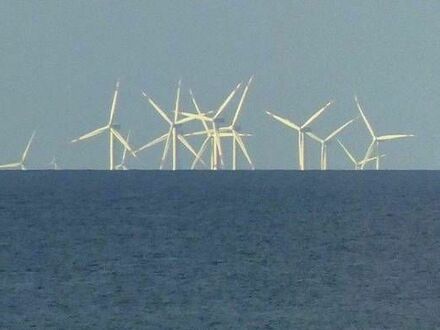 Turbiny wiatrowe wyłaniające się zza horyzontu