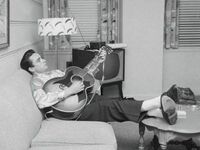 Johnny Cash grający na gitarze w pokoju hotelowym, 1958